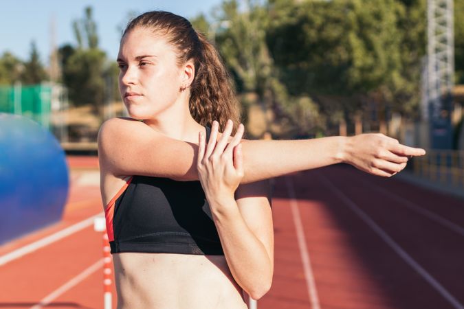 Female athlete stretching on an athletics track.