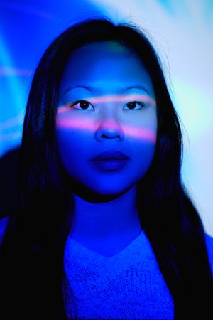 Asian woman in dark room with neon illumination