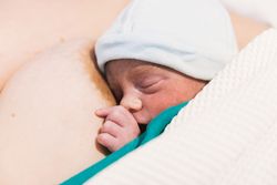 Newborn baby sleeping on mother after birth.