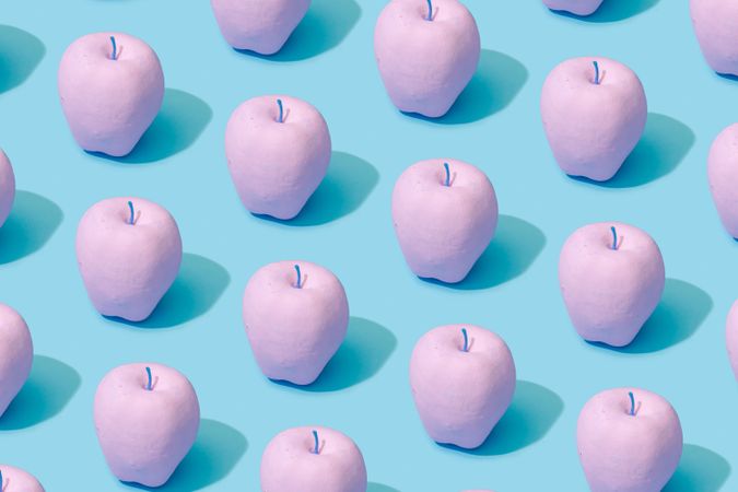 Pattern composition of pink painted apples on pastel blue background