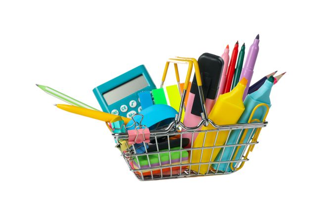 Shopping basket with school supplies isolated on neutral background