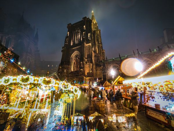 Thriving Christmas market below gothic church in Alsace, France