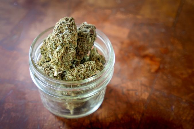 Dried marijuana in a jar on table