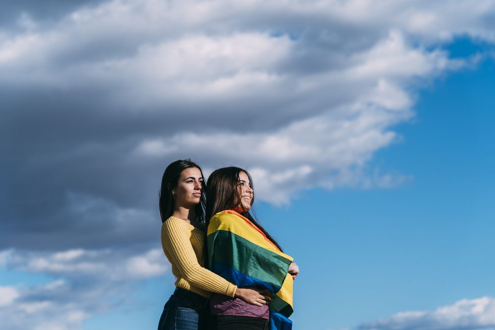 Young female couple with rainbow flag