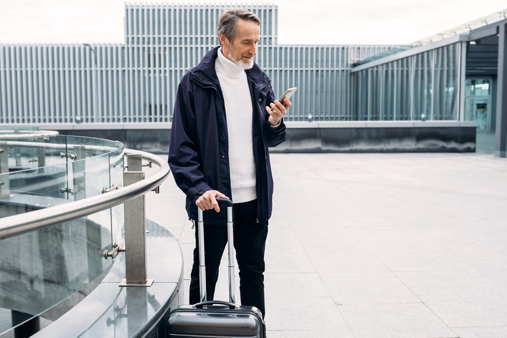 Mature man checking phone outside of airport