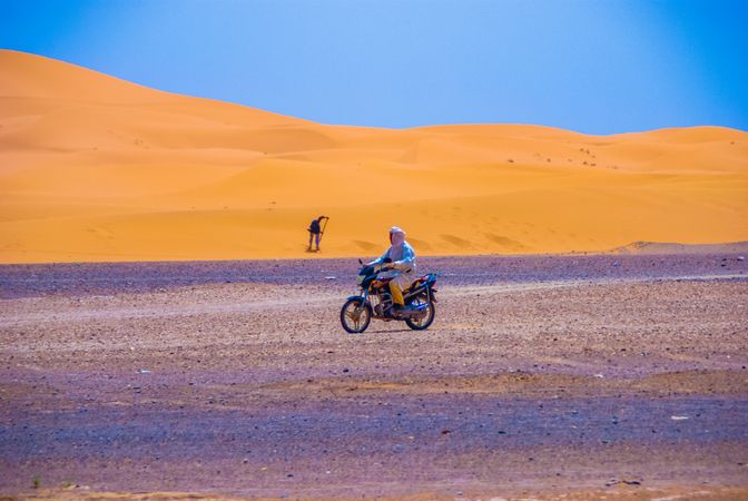 Side view of man riding a motorcycle in Moroccan desert