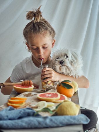 Cute little boy with small dog sitting at table