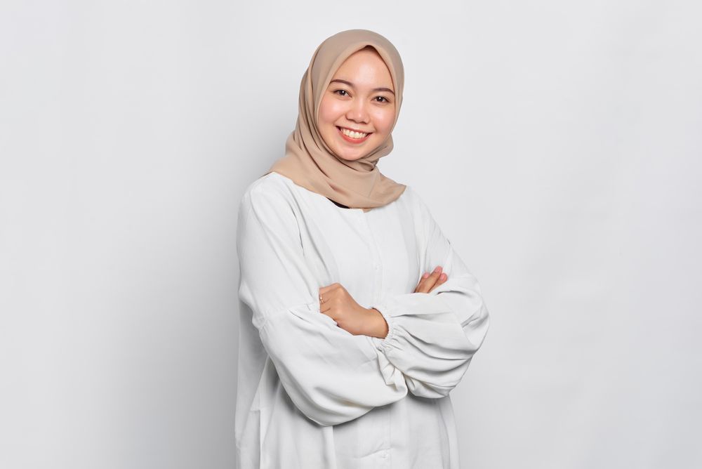 Asian female in headscarf with arms crossed and smiling at camera