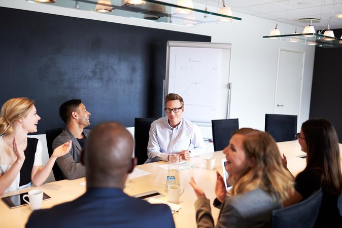 Group of businesspeople clapping for colleague