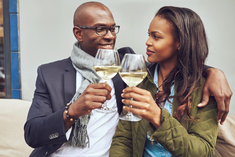 Happy Black couple looking into each others eyes with wine in hand