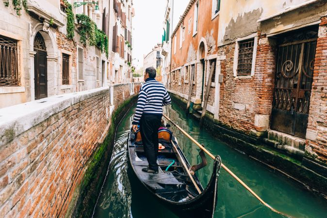 Man standing on gondola in Venetian canal