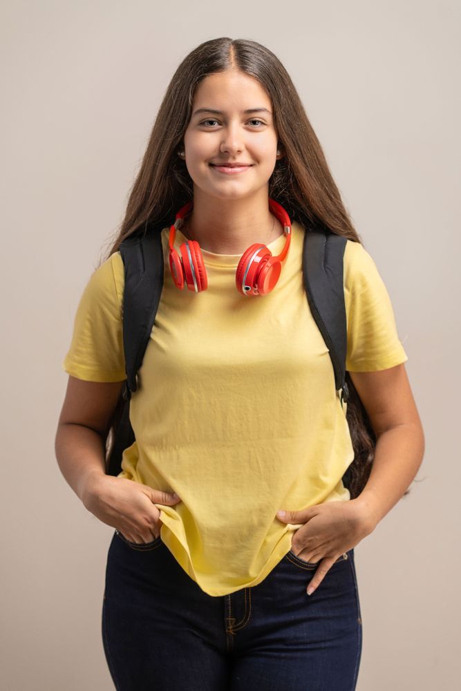 Portrait of a happy young student with a backpack and headphones looking at the camera.