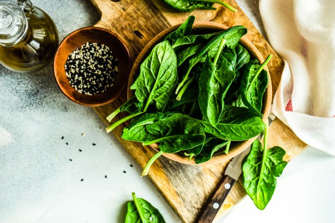 Top view of wooden bowl of fresh spinach leaves on kitchen counter