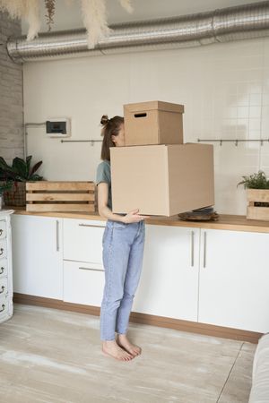Young woman carrying big carton boxes in house