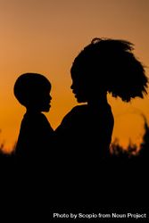 Silhouette of mother holding a baby standing outdoor at sunset 4mBjWb
