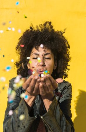 Black woman with afro hair celebrating with confetti.