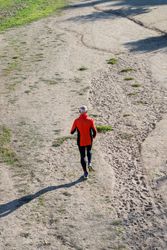 Looking down at back of male jogging in the park, vertical