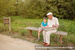 Older man and male child reading a newspaper outdoors 5o7yx5