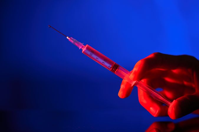 Faceless person with syringe and vaccine