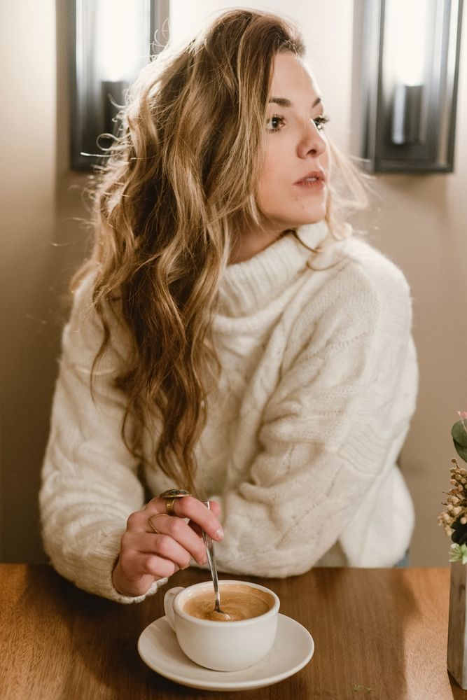 Elegant woman mixing coffee in cafe