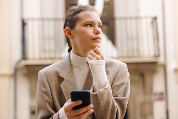 A young professional focuses on their smartphone amid a lively, energetic urban setting