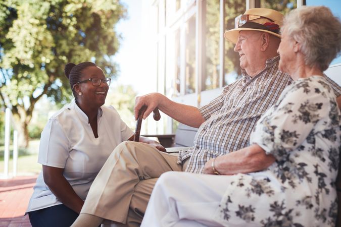 Portrait of older couple relaxing on a bench outside their retirement home