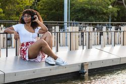 Black woman listening to music near water