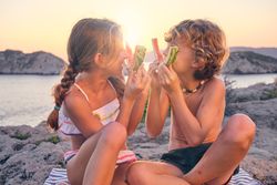 Happy brother and sister playing with watermelon rinds at seasid