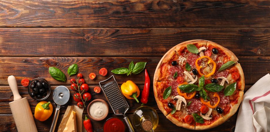 Delicious pizza and ingredients on wooden background, copy space