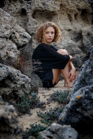 Young woman sitting between stones