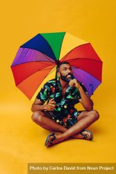 Contemplative Black male thinking about something while sitting under colorful umbrella bxkYy4