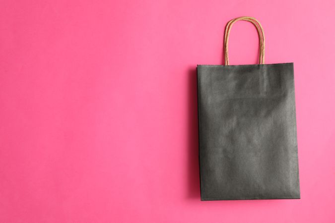 dark paper bag on pink background, space for text