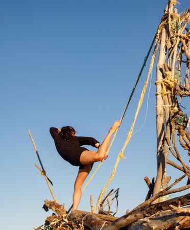 Young woman with upped leg on decorative wooden ship near water on shore