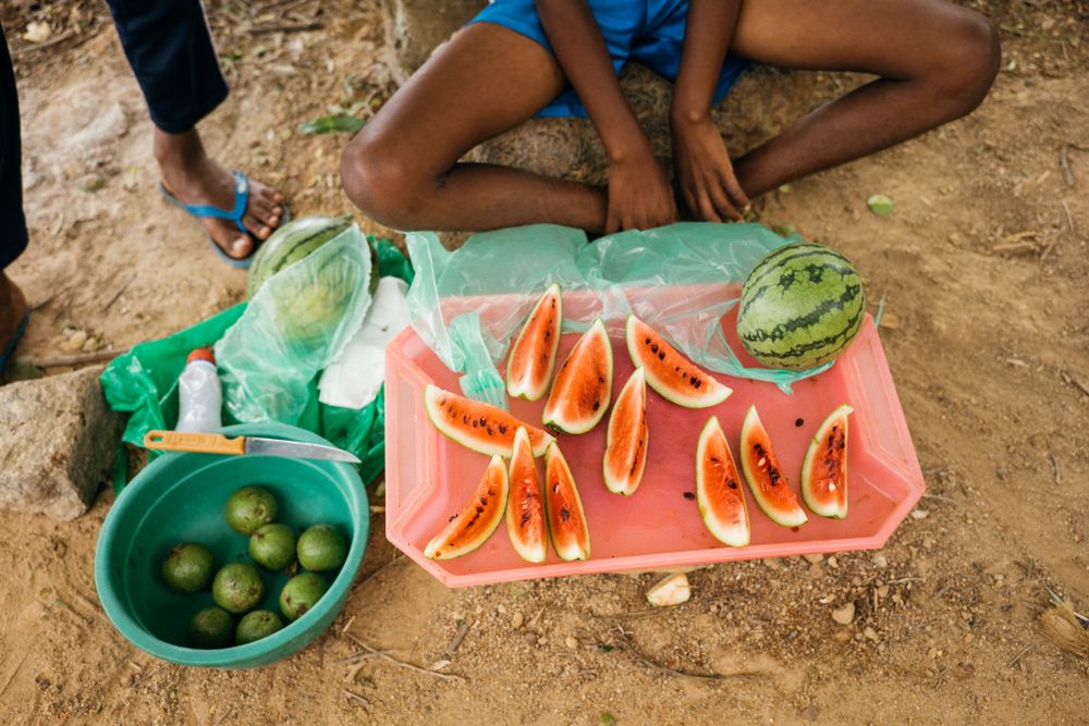 Sri Lankan person at market sitting cross legged in front of freshly cut watermelon