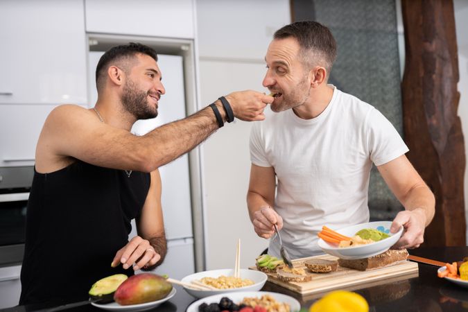 Male couple tasting meal as they prepare it