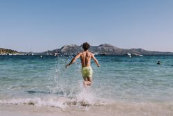 Man in swimsuit running in water on seashore
