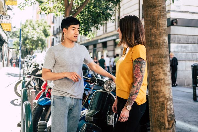 Modern multiracial couple talking while standing on street