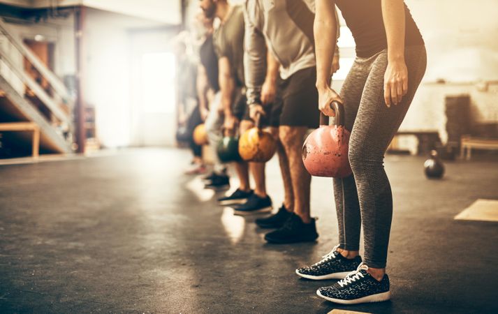 Row of people lifting kettlebells in gym class