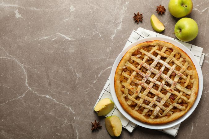 Composition with apple pie and ingredients on gray background, top view