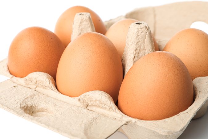 Brown chicken eggs in carton box isolated on blank background. closeup