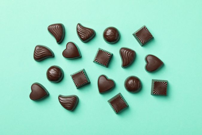 Tasty chocolate candies on mint background, top view