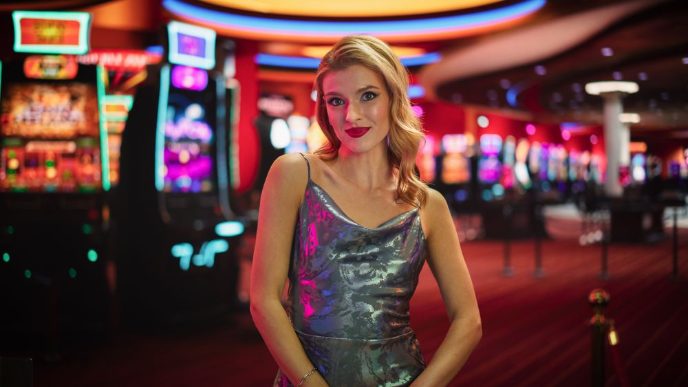 Charismatic Female Croupier Smiling, Looking At Camera And Wearing Fancy Silver Dress
