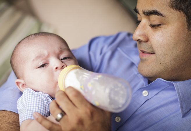 Happy Hispanic Father Bottle Feeding His Son