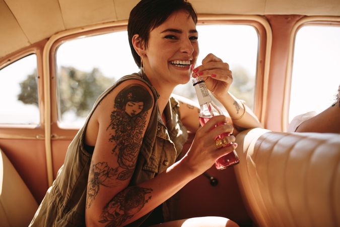 Woman with tattoos sitting in the back of a vintage car