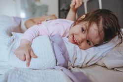 Close up cute little girl playing in bed