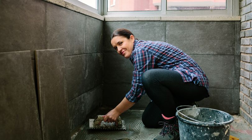 Female mason laying a new tile floor