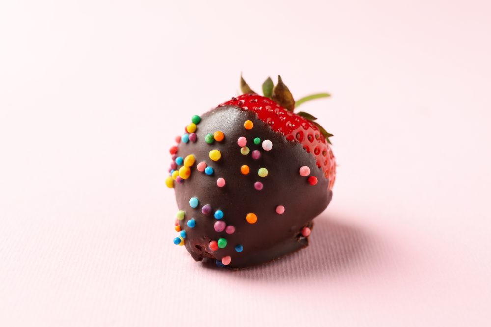 Chocolate fondue. Strawberry in chocolate on pink background