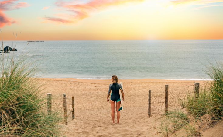 Woman standing on sand gazing out at beautiful ocean view