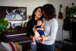 Two woman looking at each other while holding their newborn baby