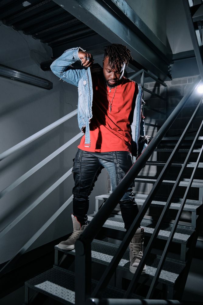 Black man putting on jacket on metal stairs